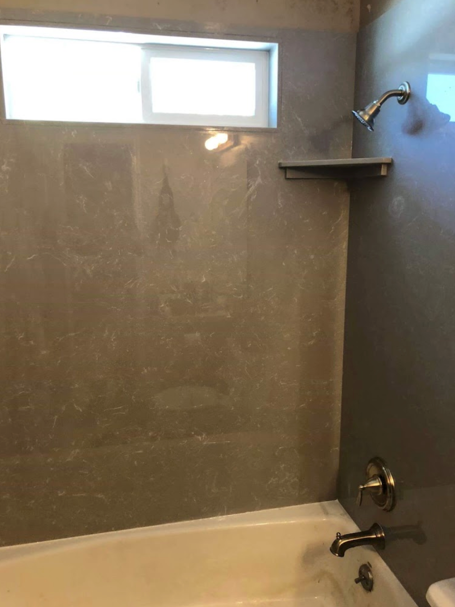 A bathroom with a bathtub , shower , and window.