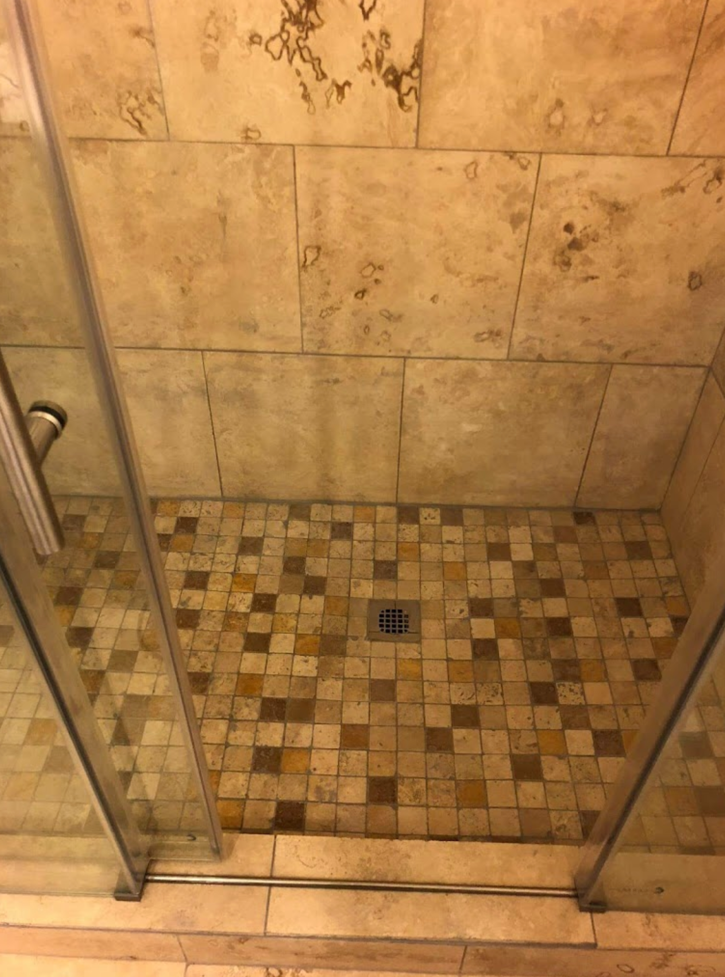A shower stall with a tiled floor and a glass door.