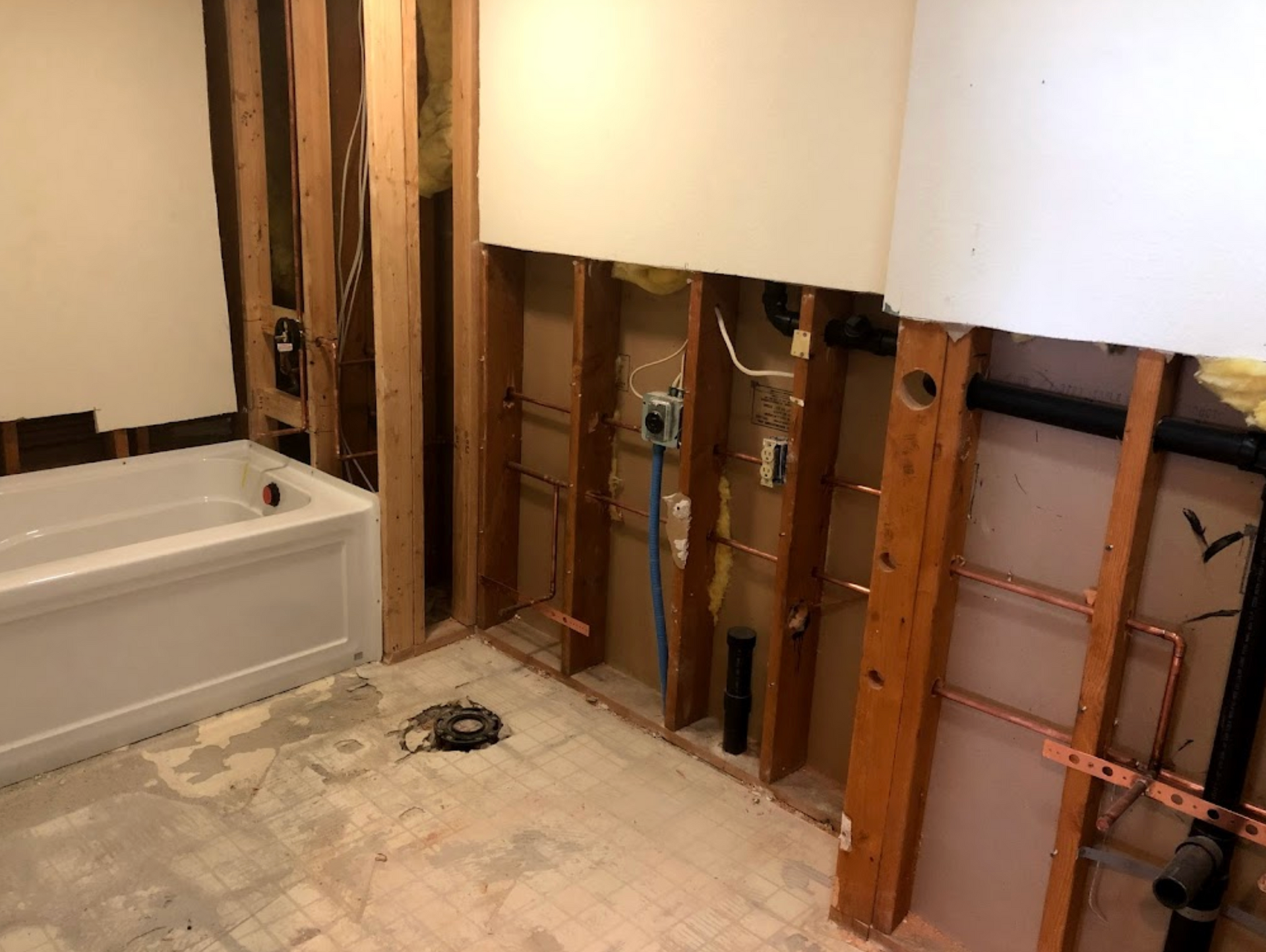 A bathroom under construction with a bathtub and pipes.