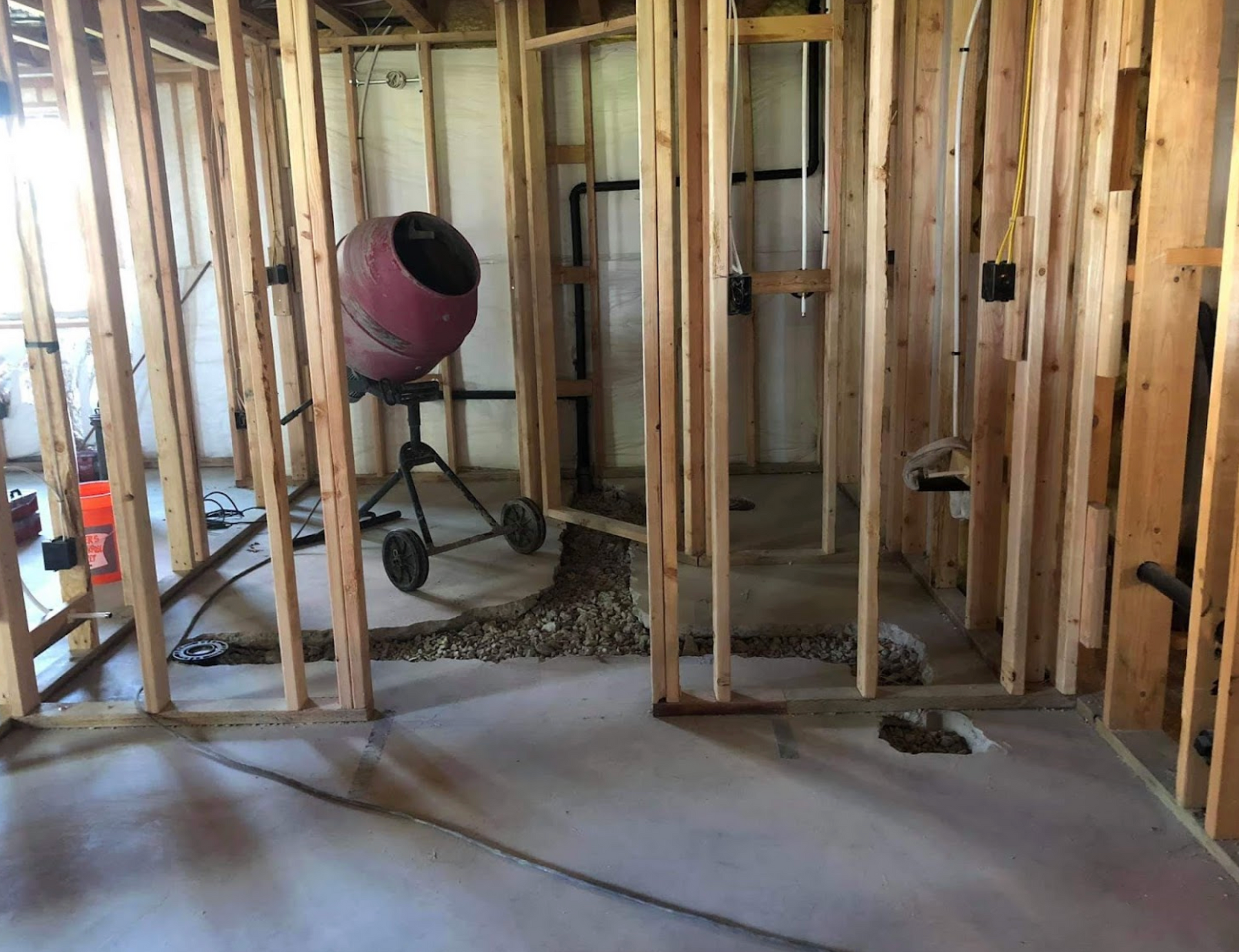 A concrete mixer is sitting in the middle of a room under construction.