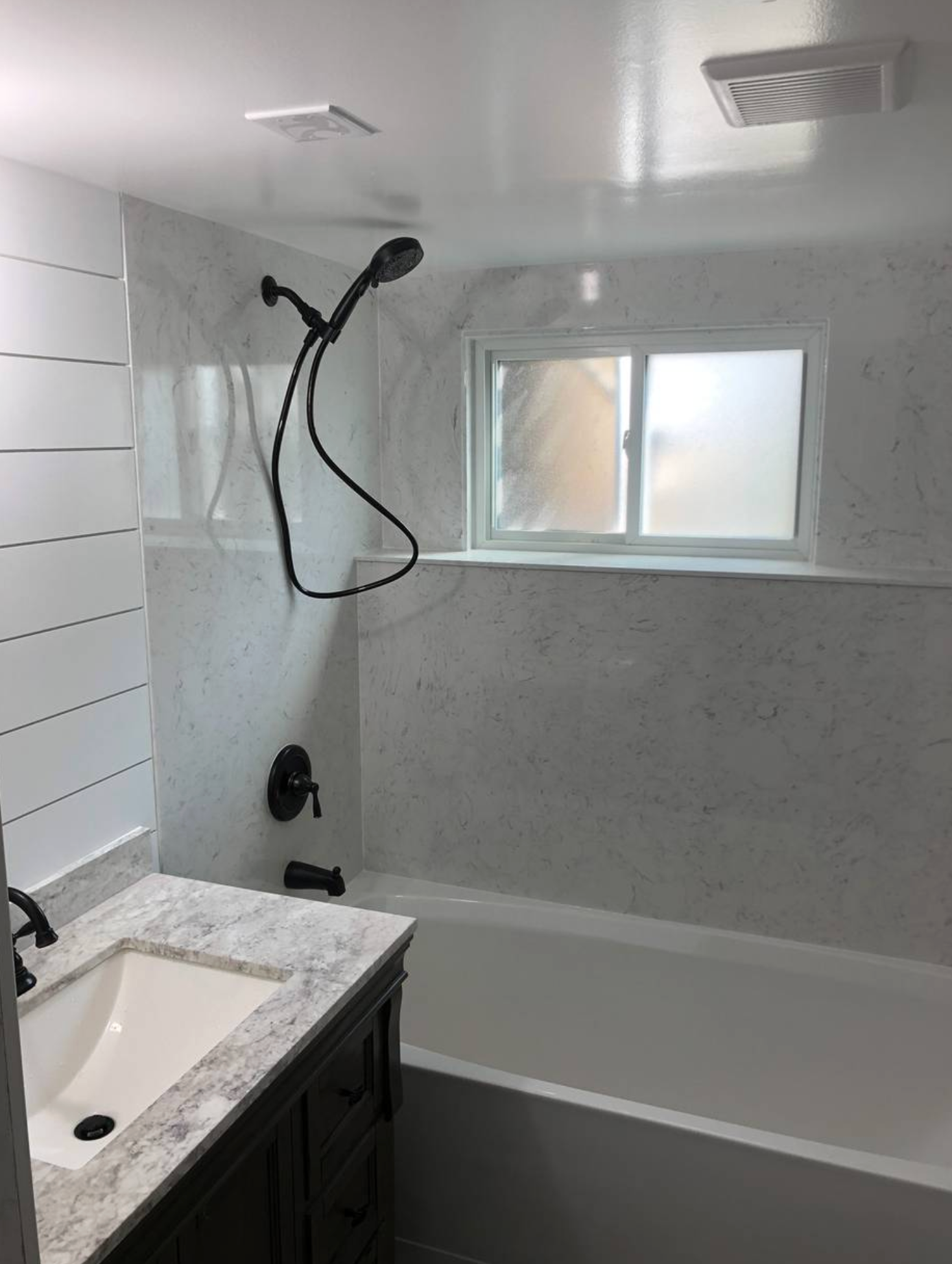 A bathroom with a sink , tub , shower and window.