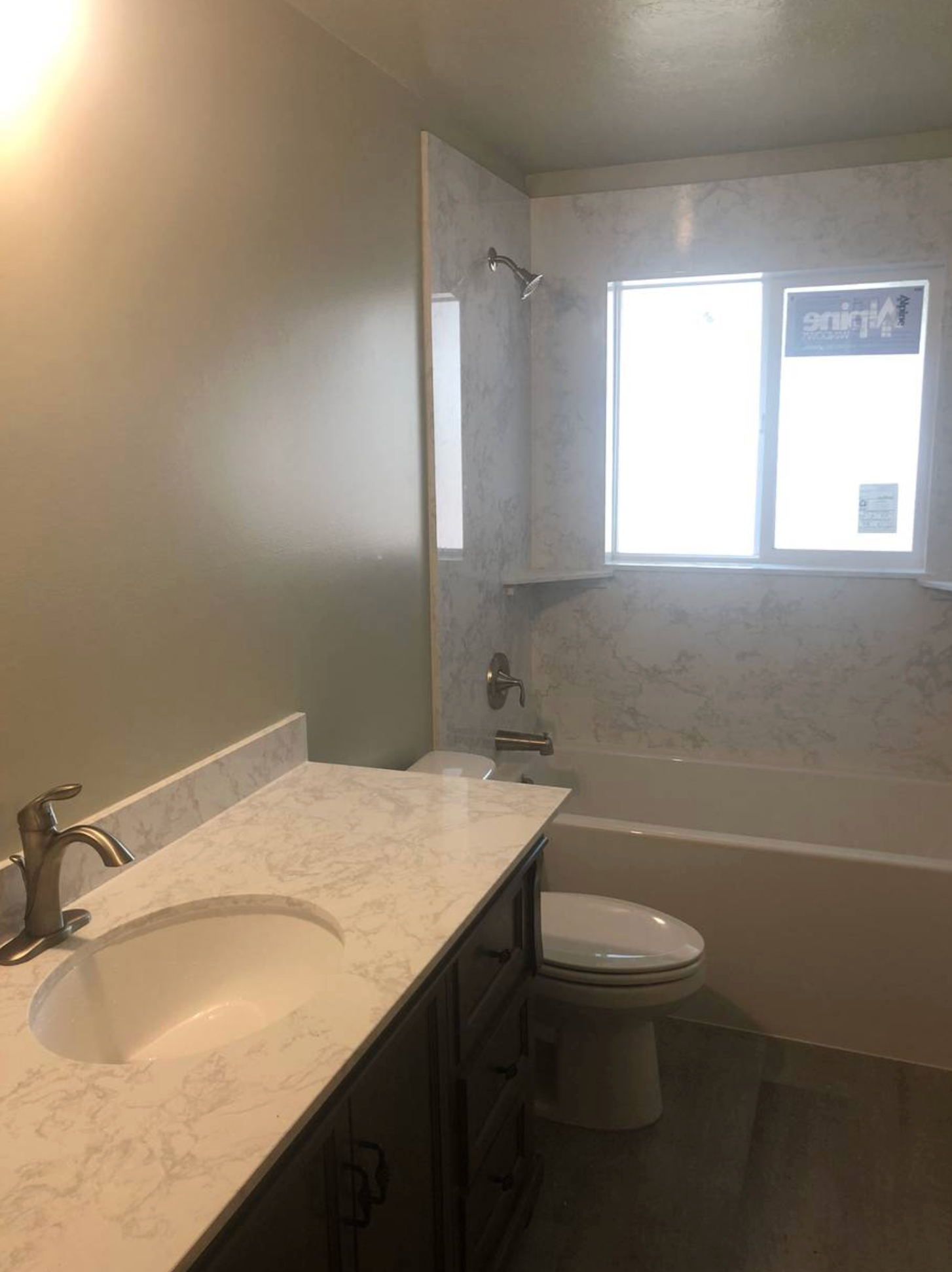 A bathroom with a sink , toilet , tub and window.