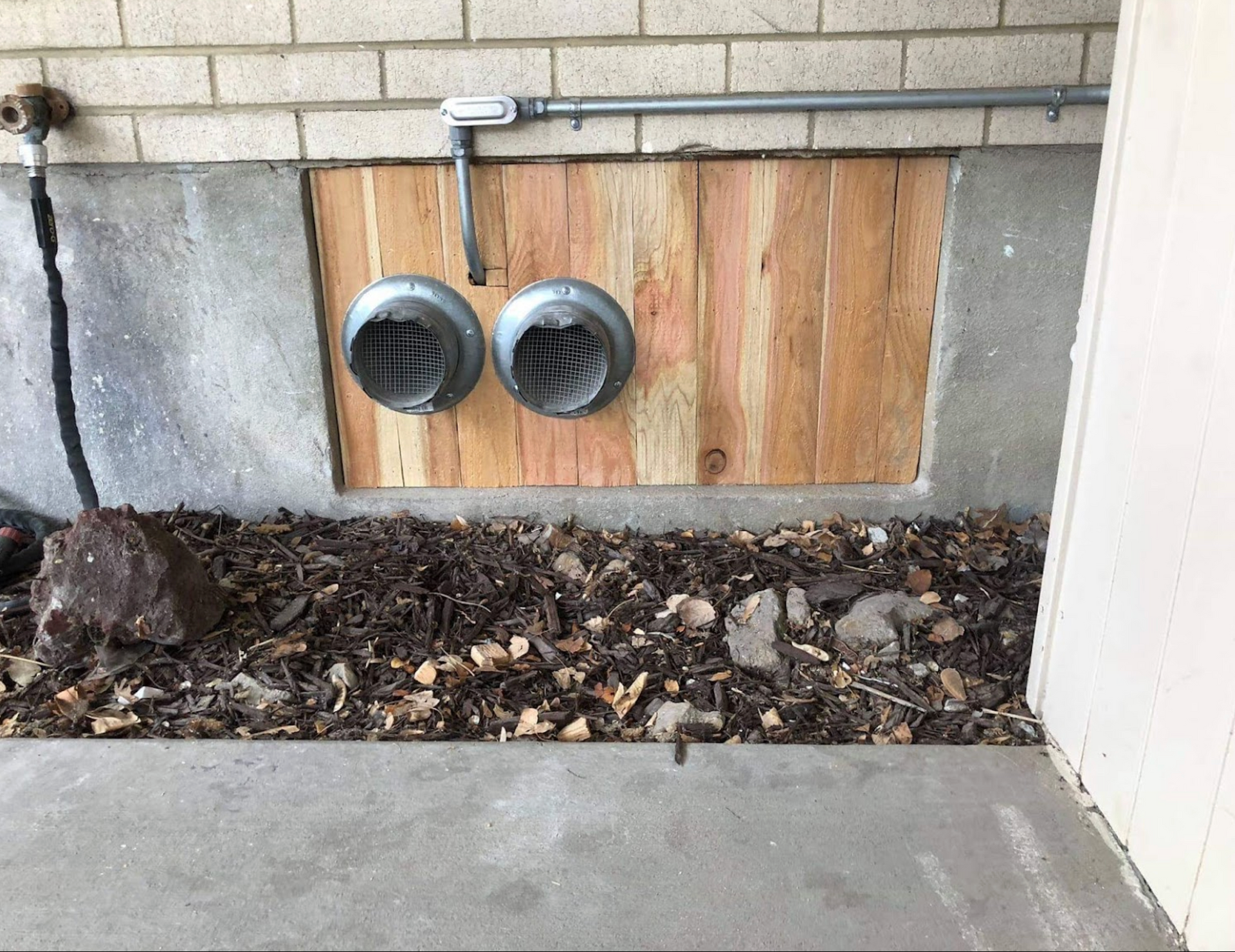 A wooden wall with two pipes coming out of it.