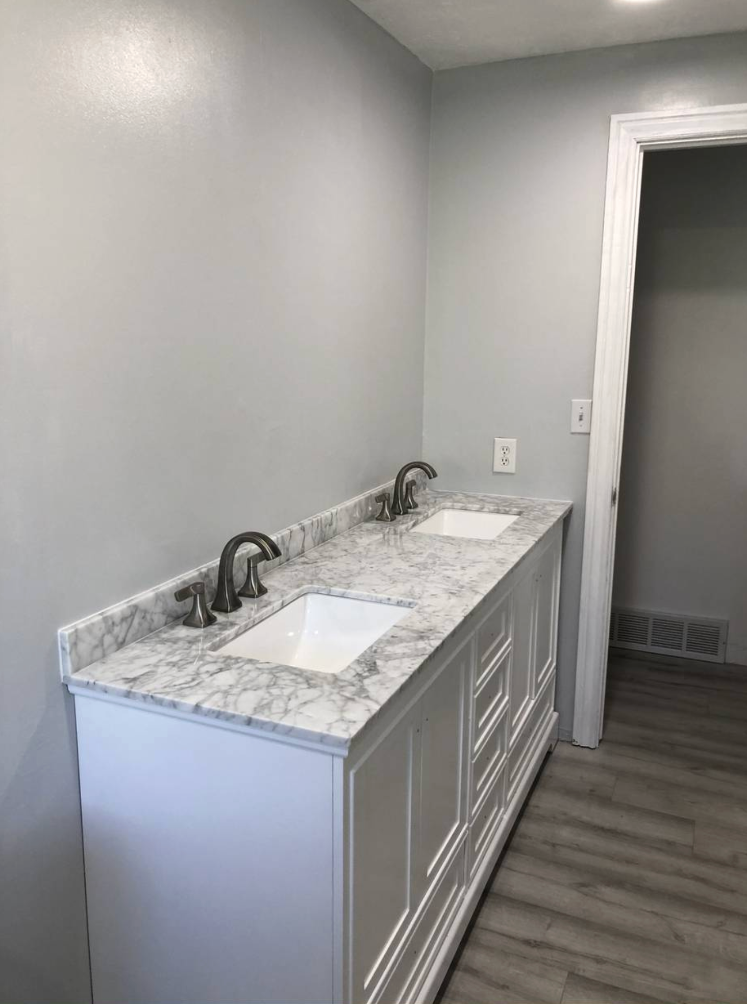 A bathroom with two sinks and a marble counter top.
