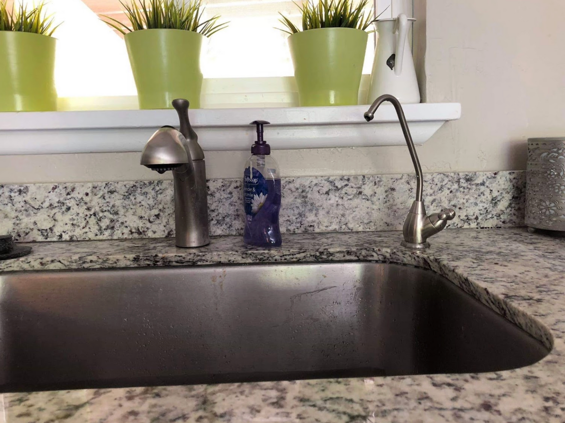 A kitchen sink with a soap dispenser on the counter.