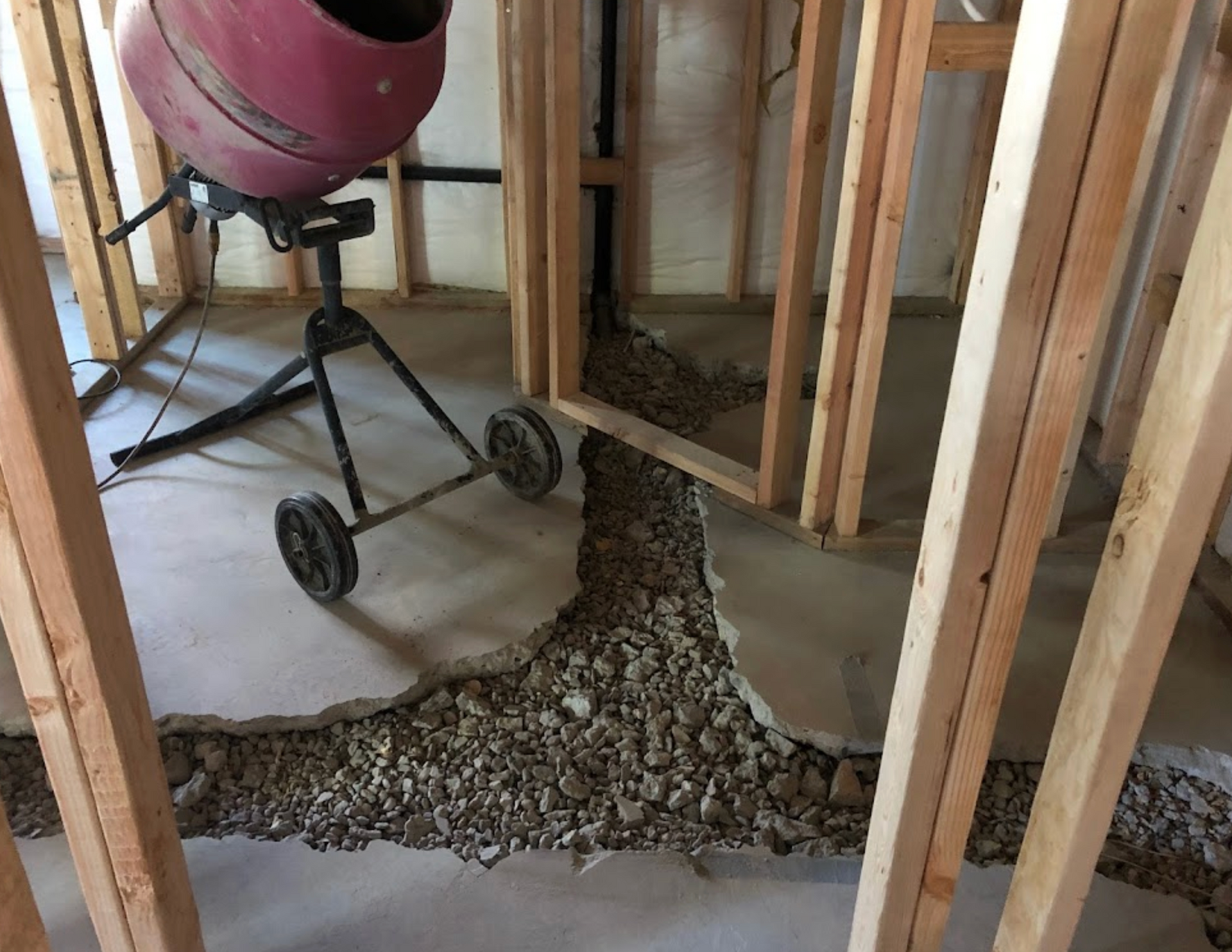 A red cement mixer is sitting in a room under construction.