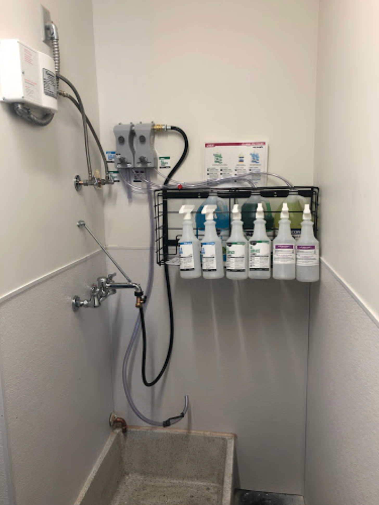 A bathroom with a sink and spray bottles on the wall