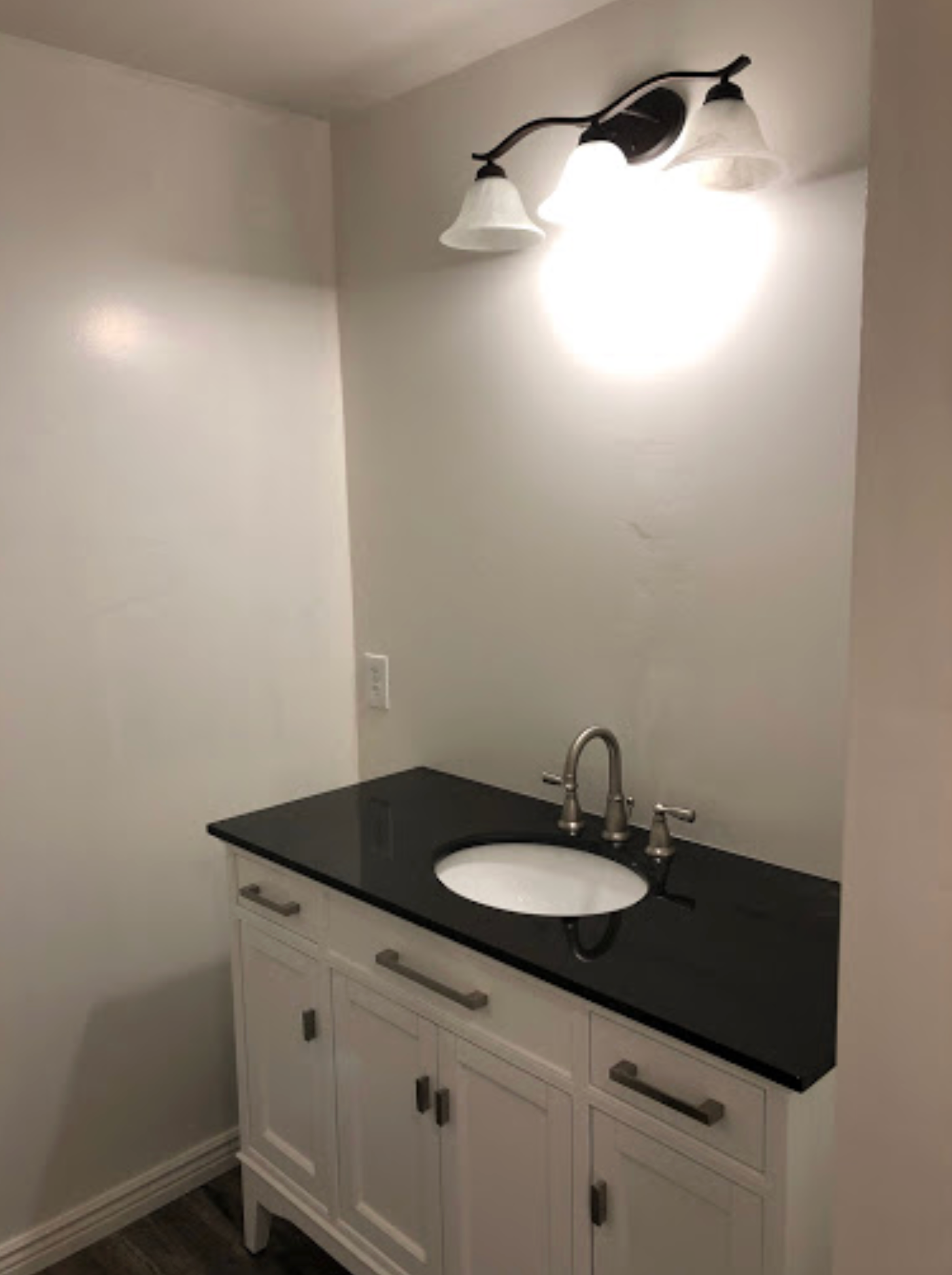 A bathroom with a black counter top and a white sink