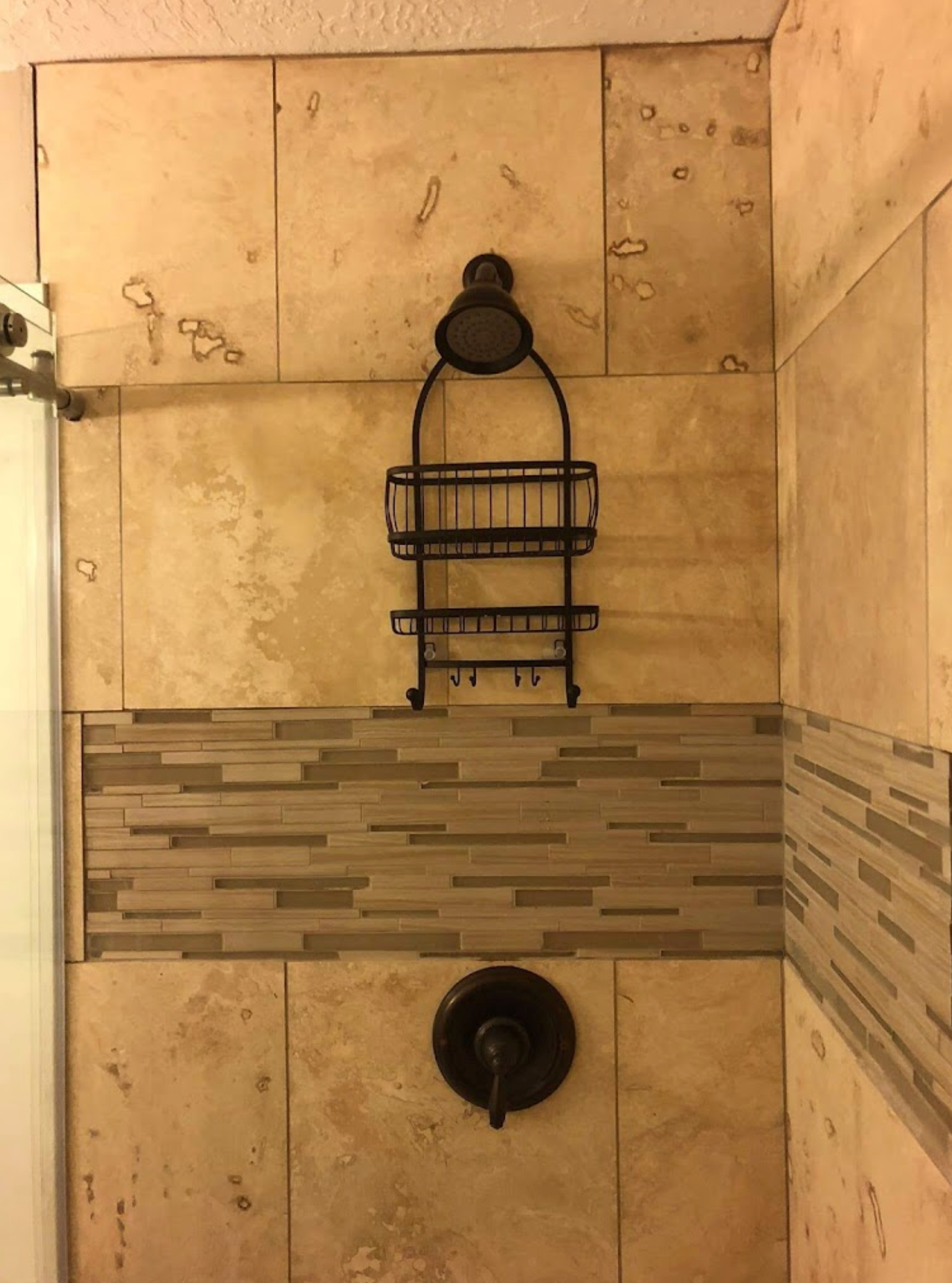 A shower stall with a shower caddy hanging from the wall