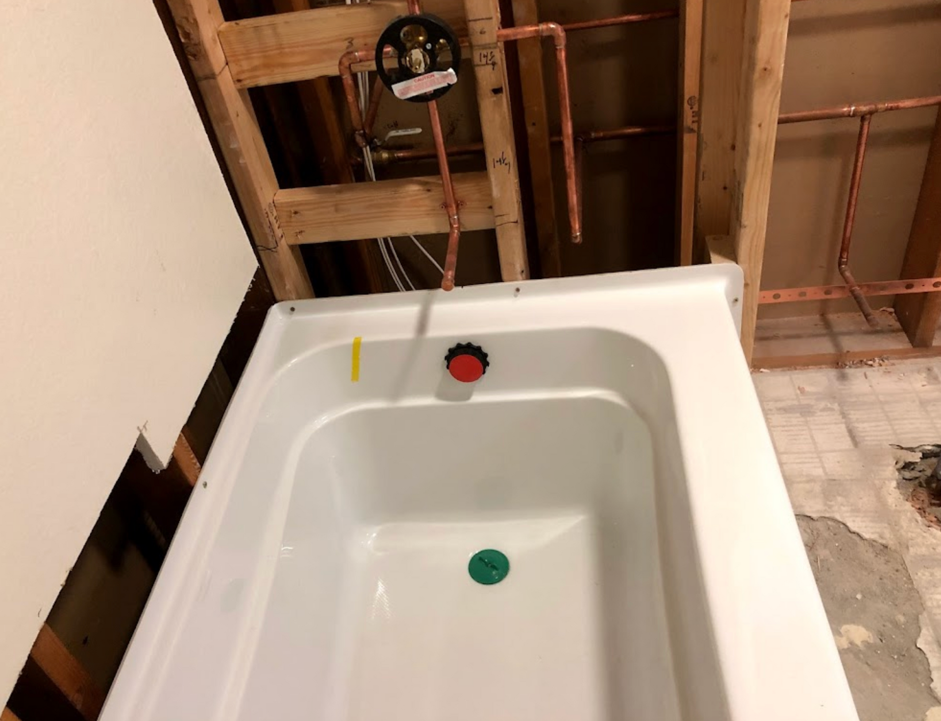 A bathtub in a bathroom under construction with copper pipes
