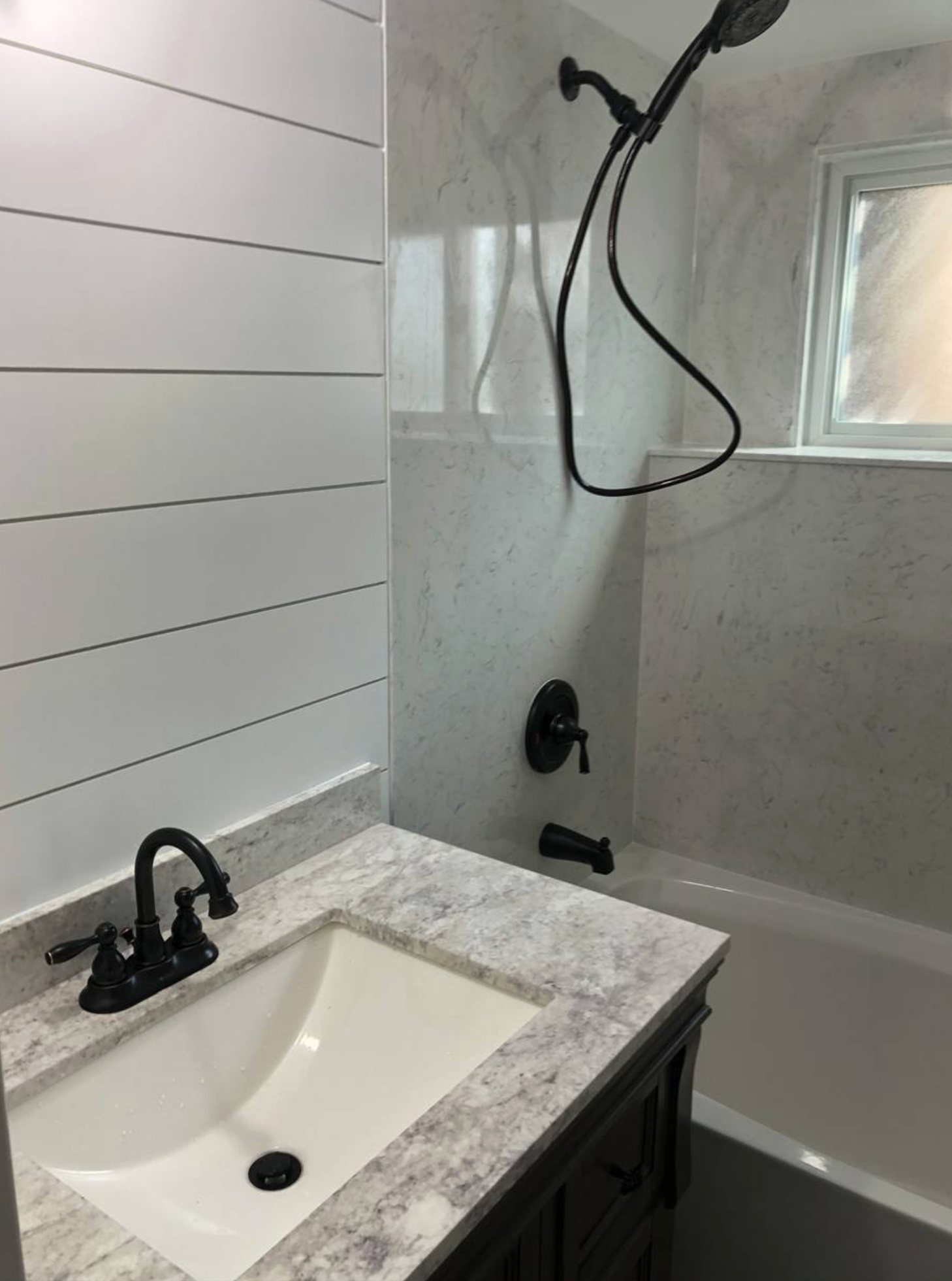 A bathroom with a sink , tub and shower.