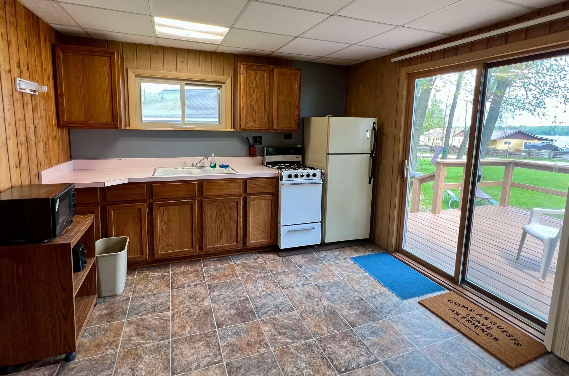Kitchen with wooden cabinets, pink countertops, and a sliding glass door to a deck.