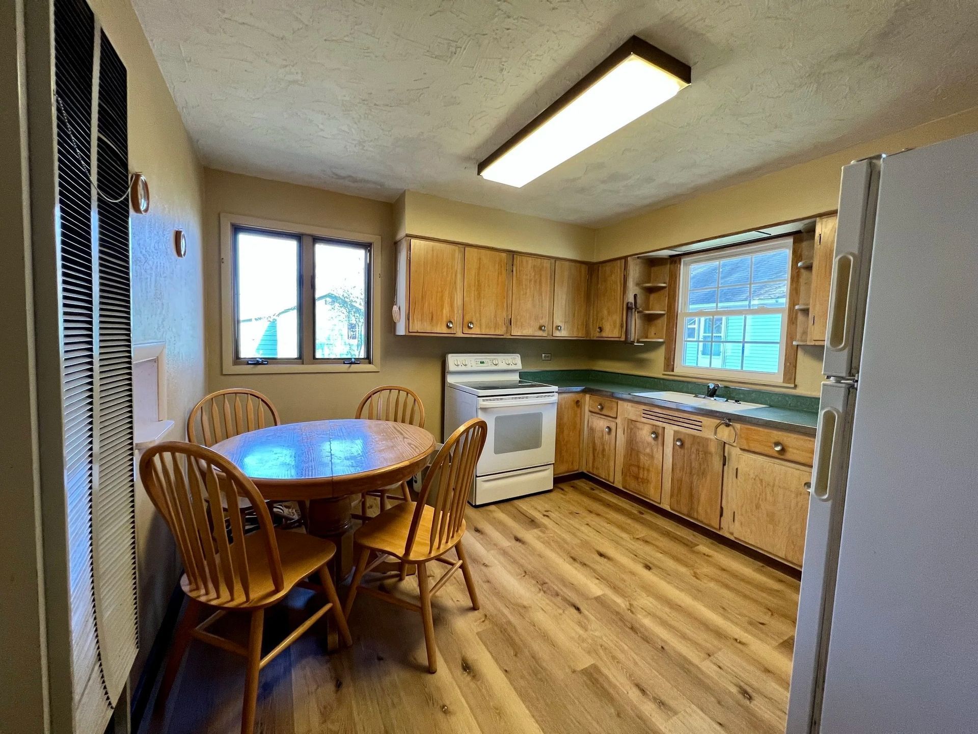 Kitchen with wood cabinets, round table, chairs, and appliances.