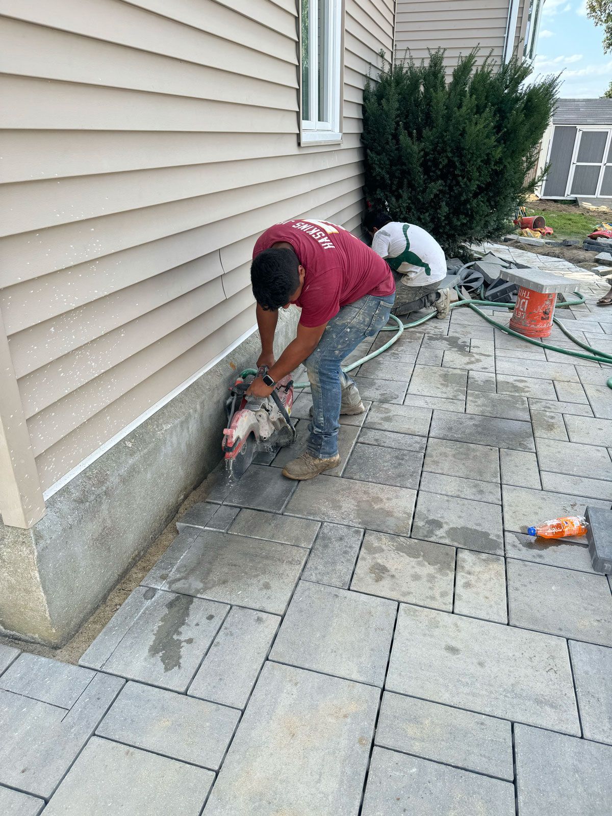 A man is cutting bricks with a chainsaw on a sidewalk.