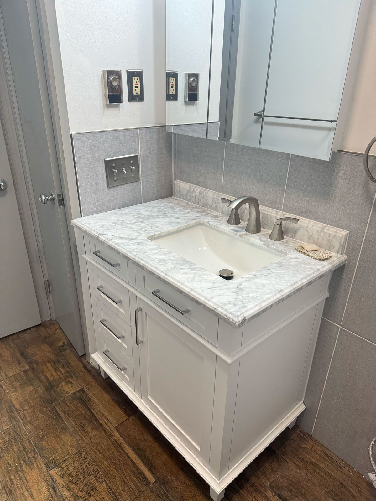 A bathroom with a white vanity , sink and mirror.