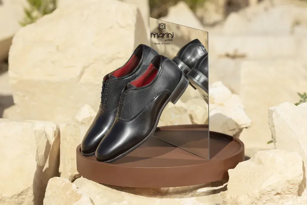 Scarpe eleganti in pelle nera esposte su una zeppa marrone con retro a specchio.