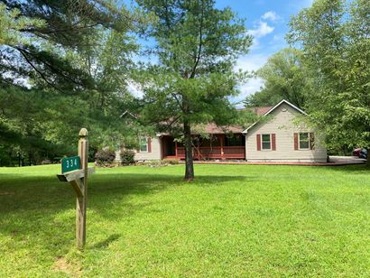 A house is sitting in the middle of a lush green field surrounded by trees.