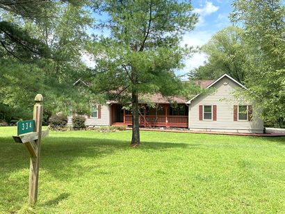 A resort ranch home sitting in the middle of a lush green field surrounded by trees.
