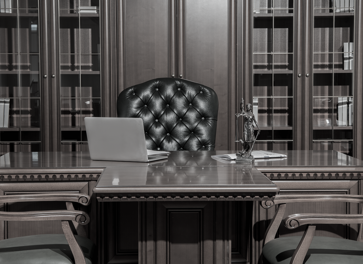 A black and white photo of a lawyer 's office with a laptop on the desk.