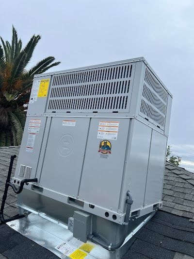 A large gray box is sitting on top of a roof next to a palm tree.