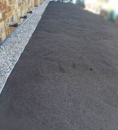 A black asphalt driveway next to a stone wall.