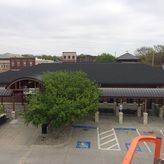 A large building with a black roof and a tree in front of it.