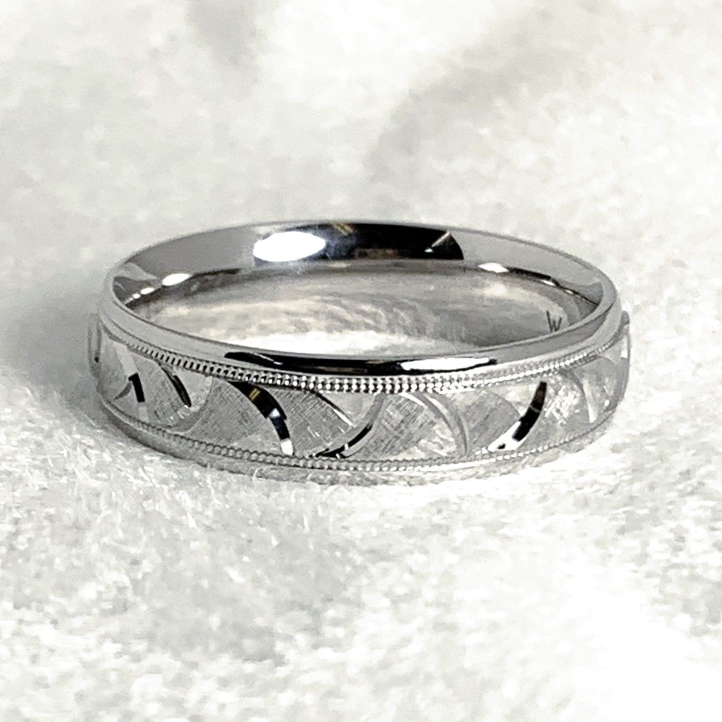 A close up of a silver ring on a white surface.