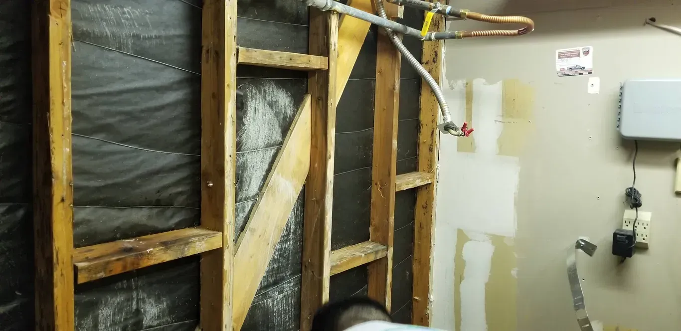 A man is working on a wall in a basement.