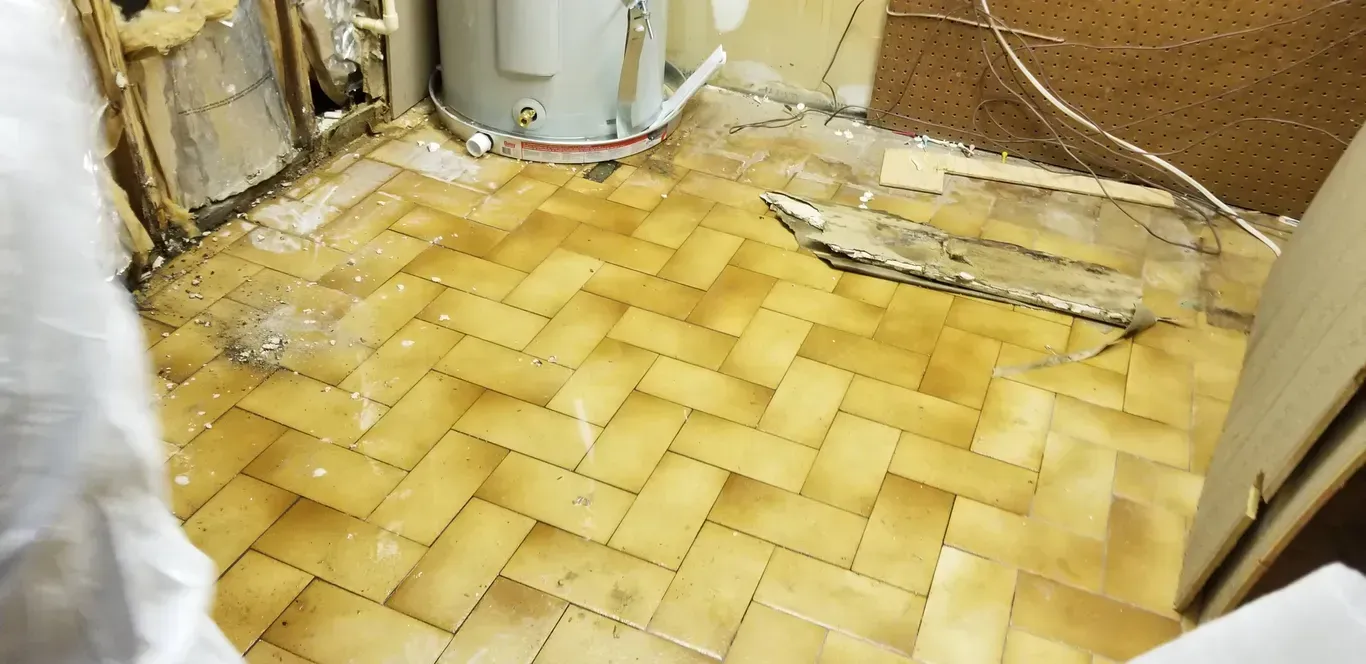 A water heater is sitting on a tiled floor in a room.