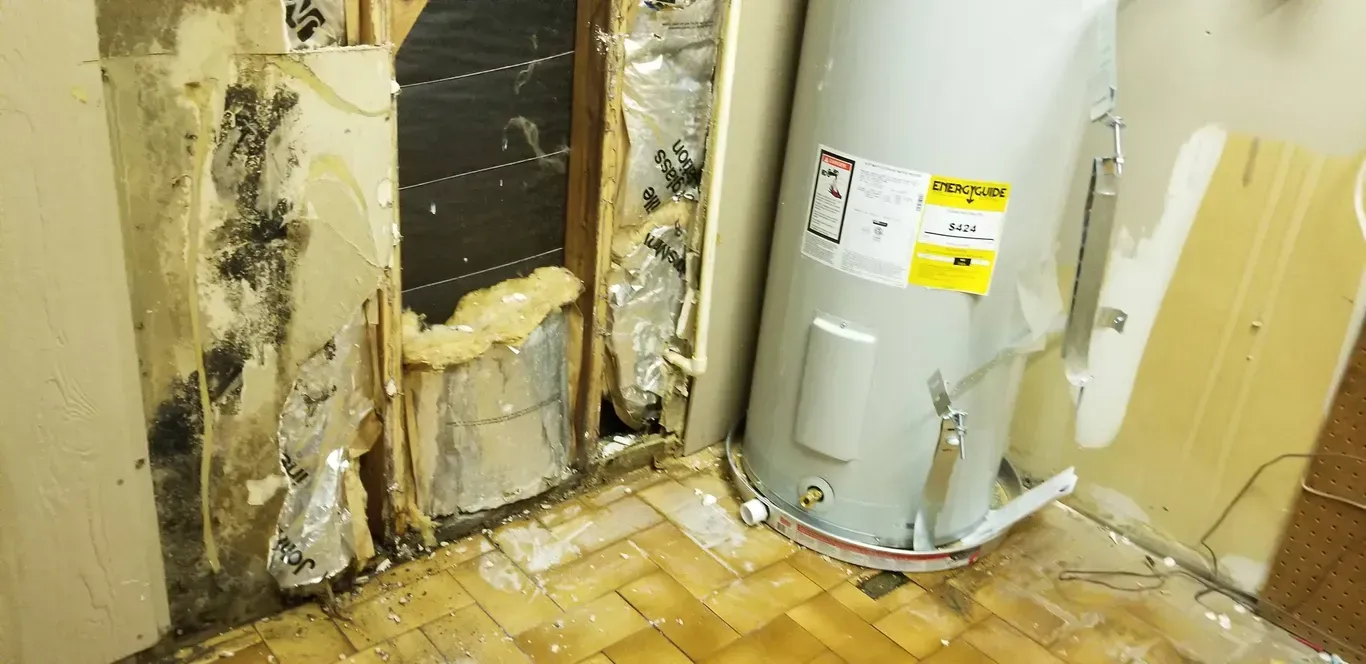 A water heater is sitting in a room next to a wall.