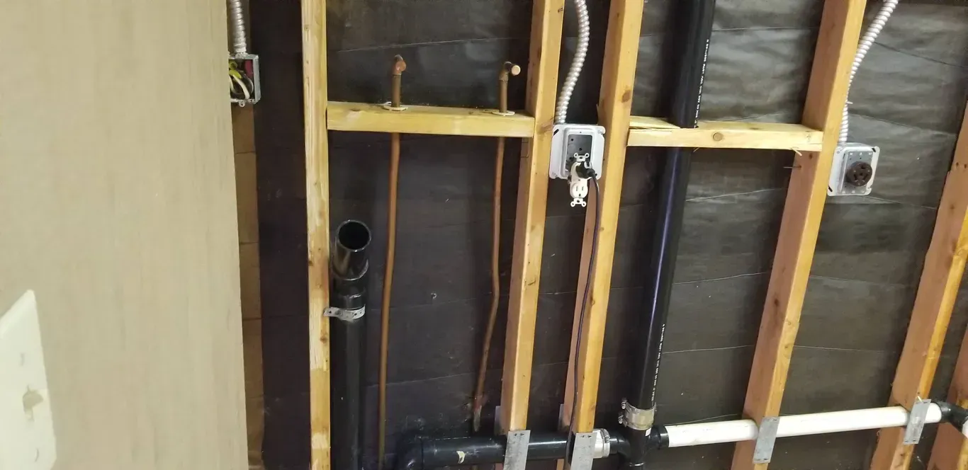 A bathroom with a lot of pipes hanging from the ceiling.