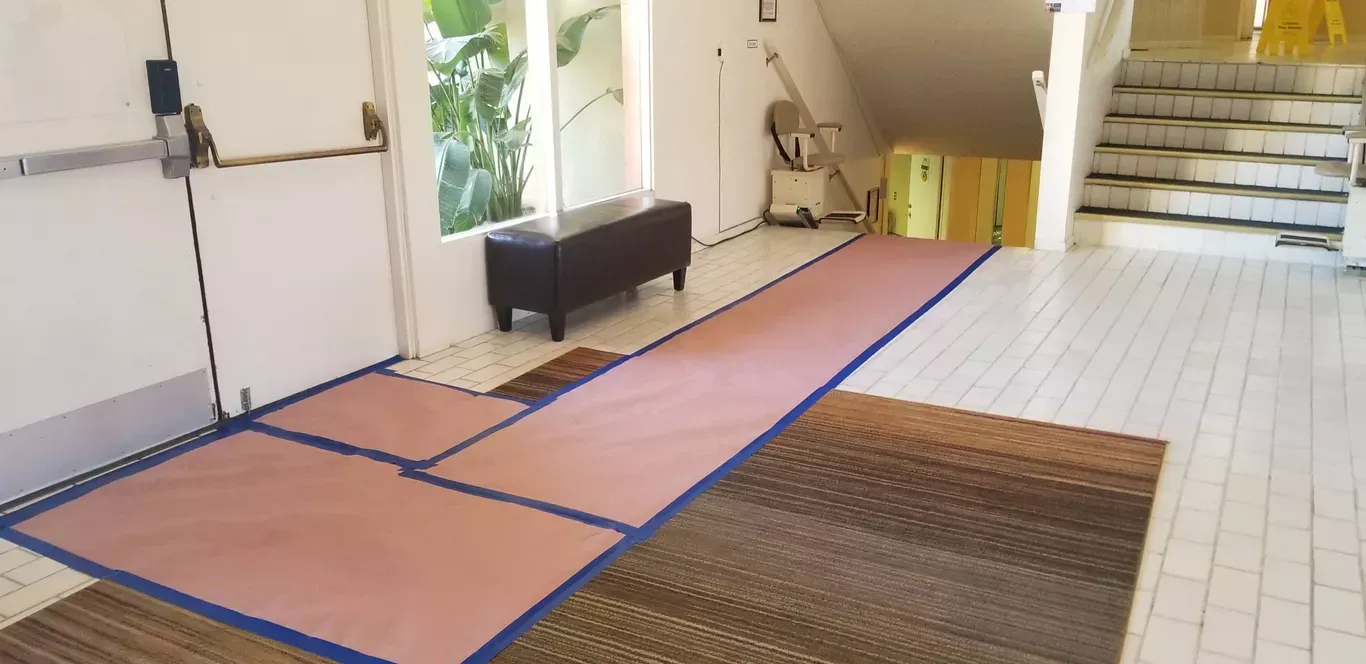 A hallway with a staircase in the background and a rug on the floor.