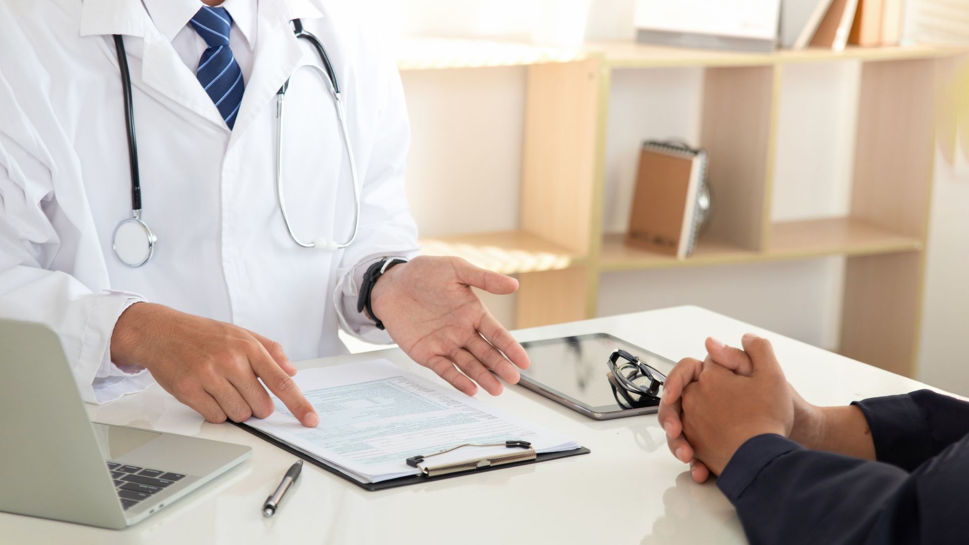 A doctor is talking to a patient while sitting at a desk.