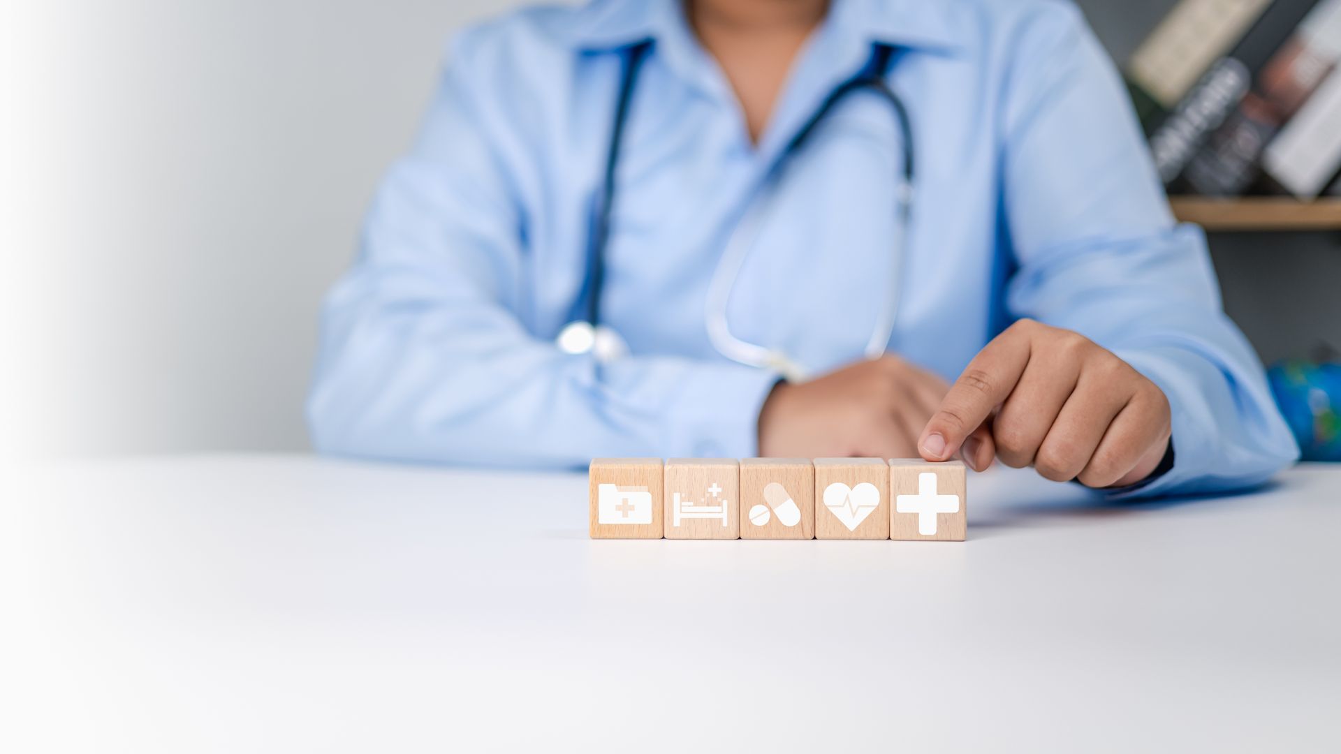 A doctor is sitting at a table playing with wooden blocks.