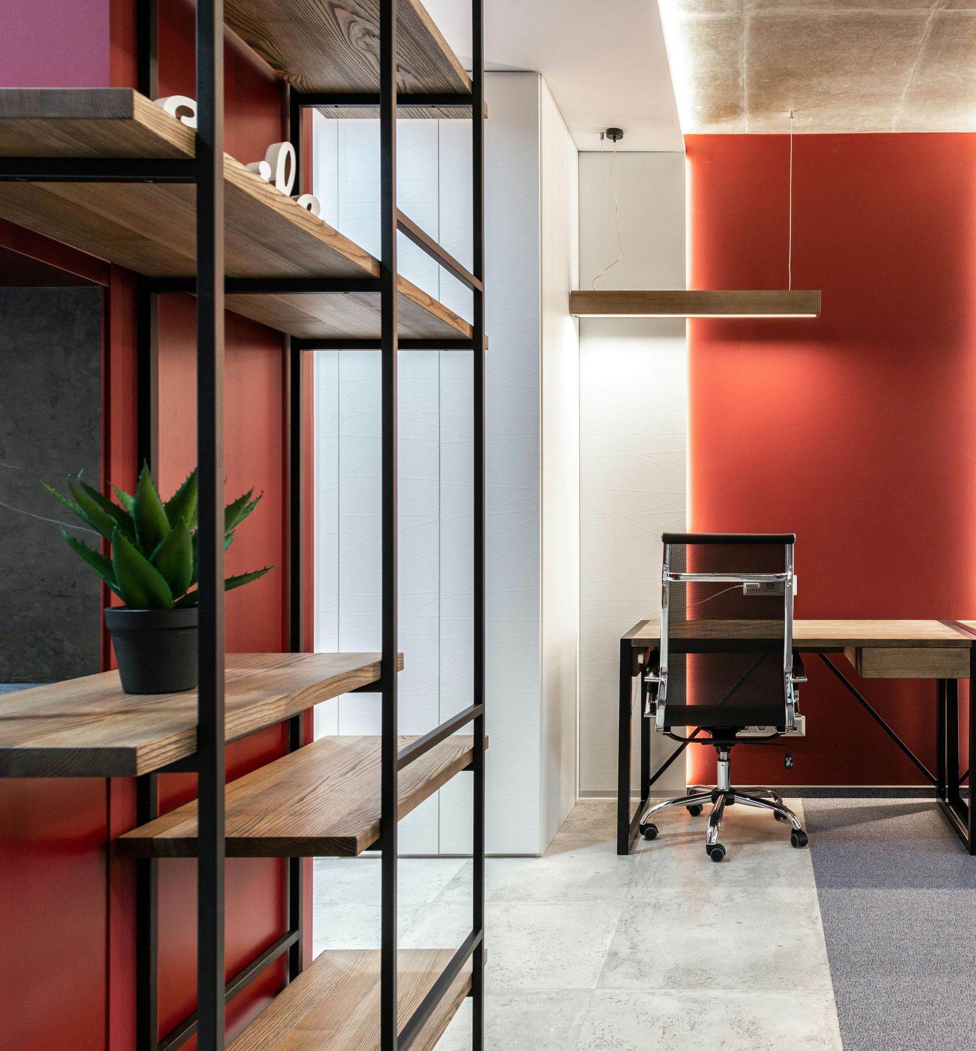 A room with a red wall and a desk and chair