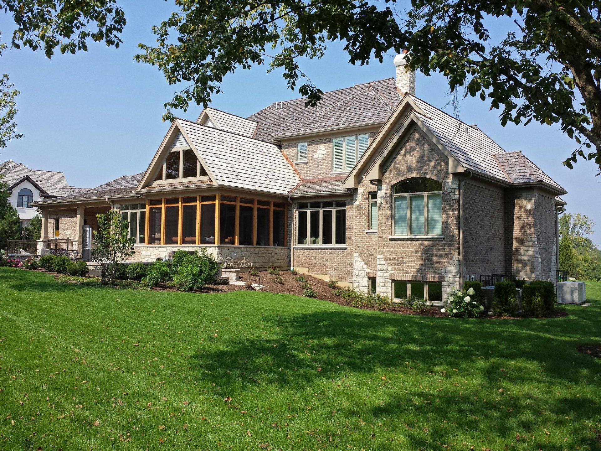A large brick house sits in the middle of a lush green field