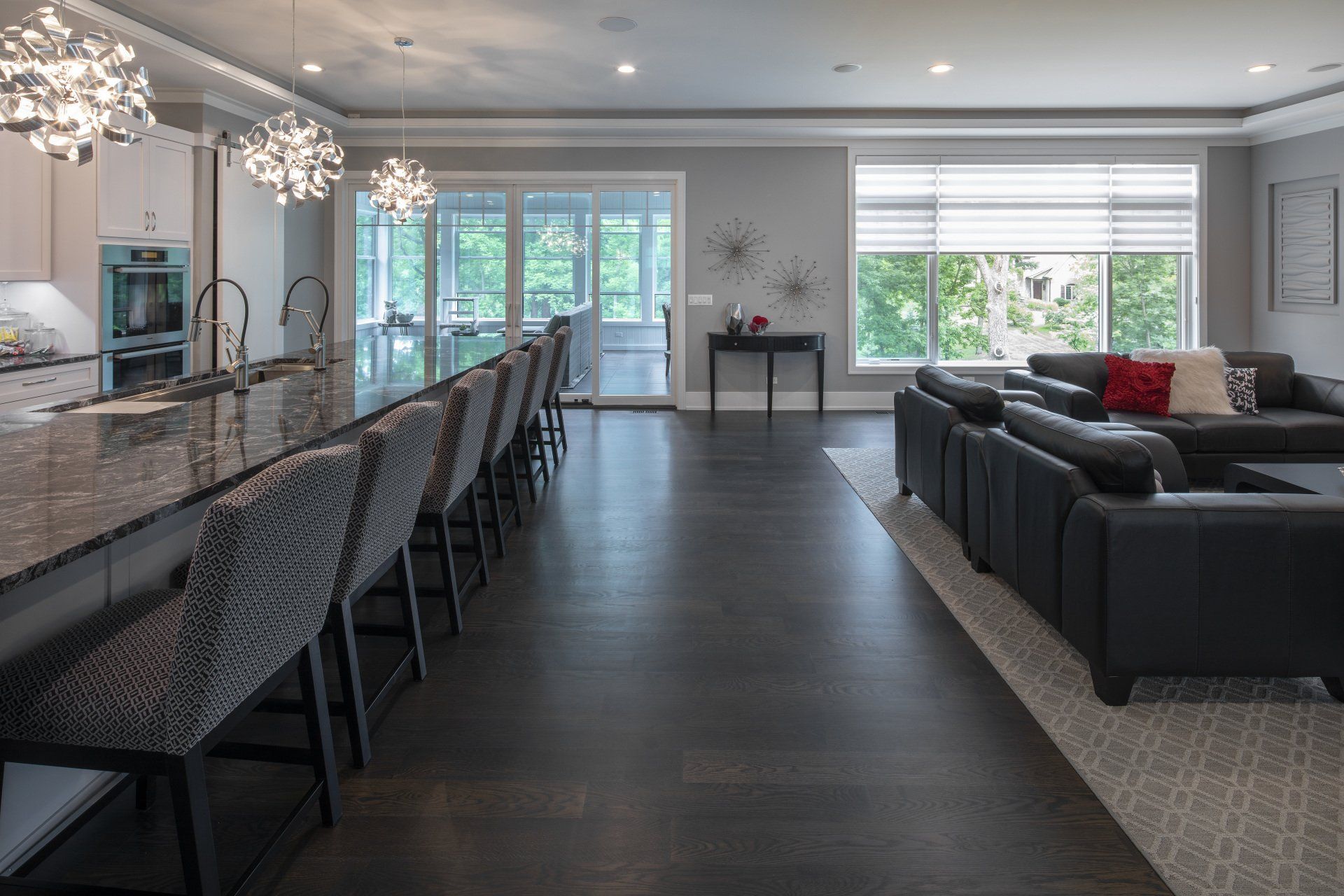 A large living room with a couch , chairs , and a kitchen.