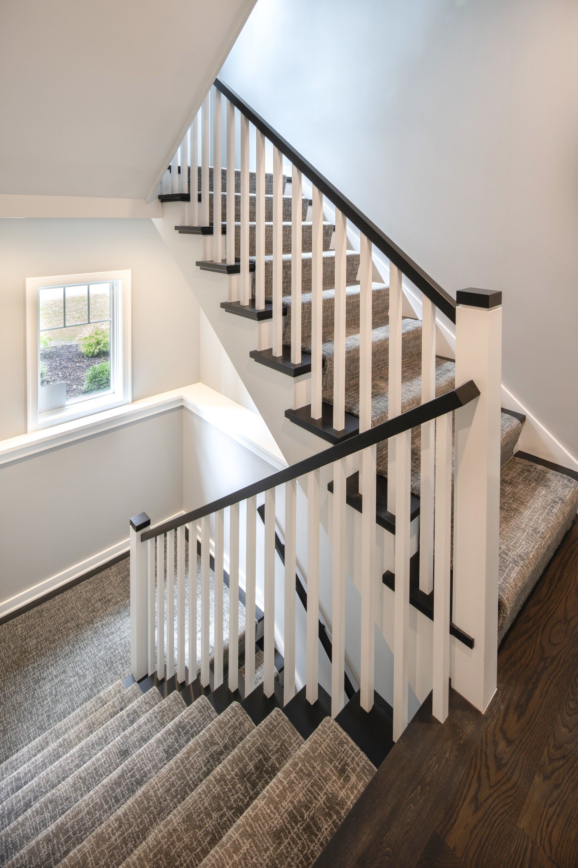 A staircase with a white railing and a window in the background.