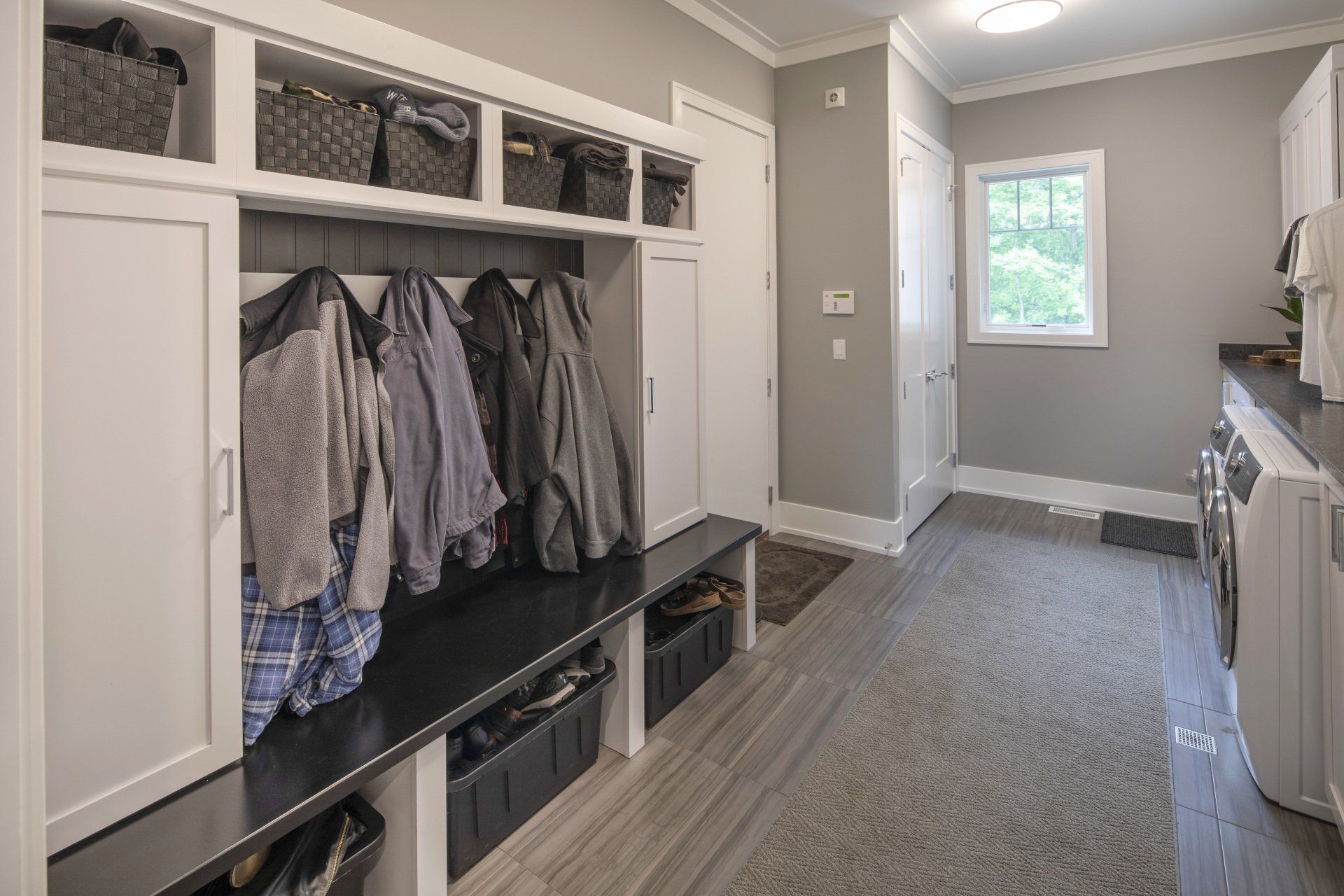 A laundry room with a bench and a washer and dryer.