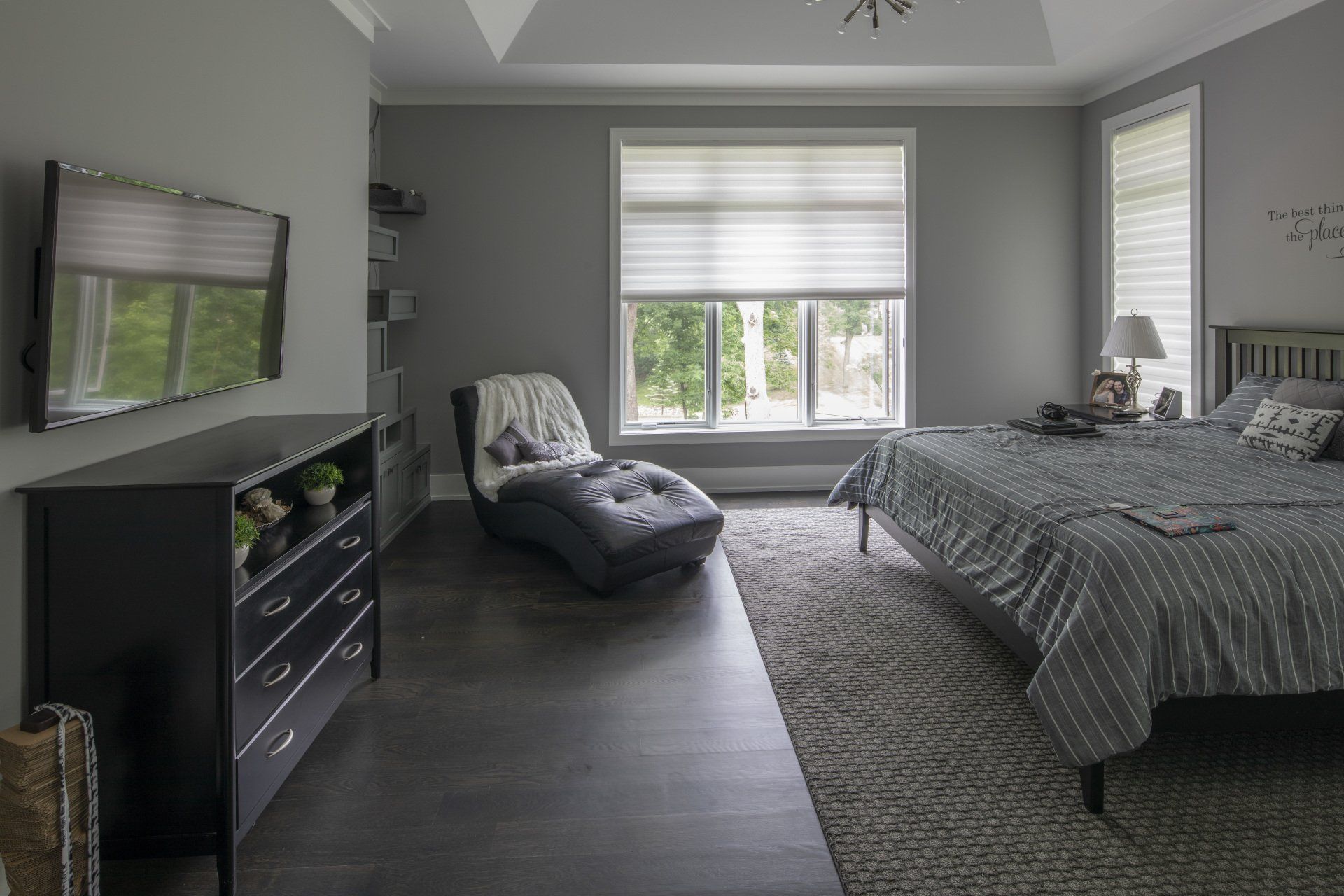A bedroom with a bed , dresser , chair and television.