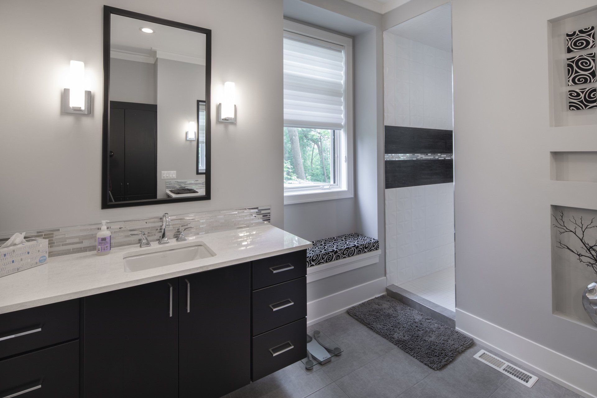 A bathroom with a sink , mirror , and window.