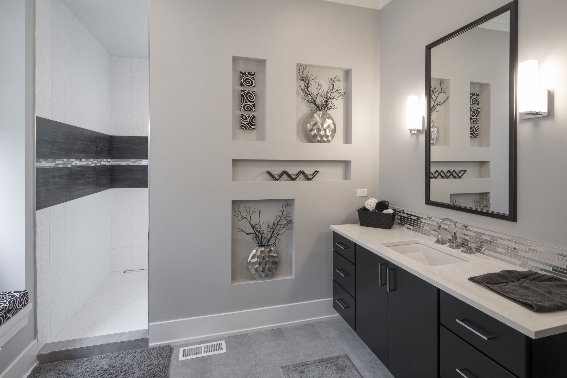 A bathroom with two sinks , a mirror and a walk in shower.