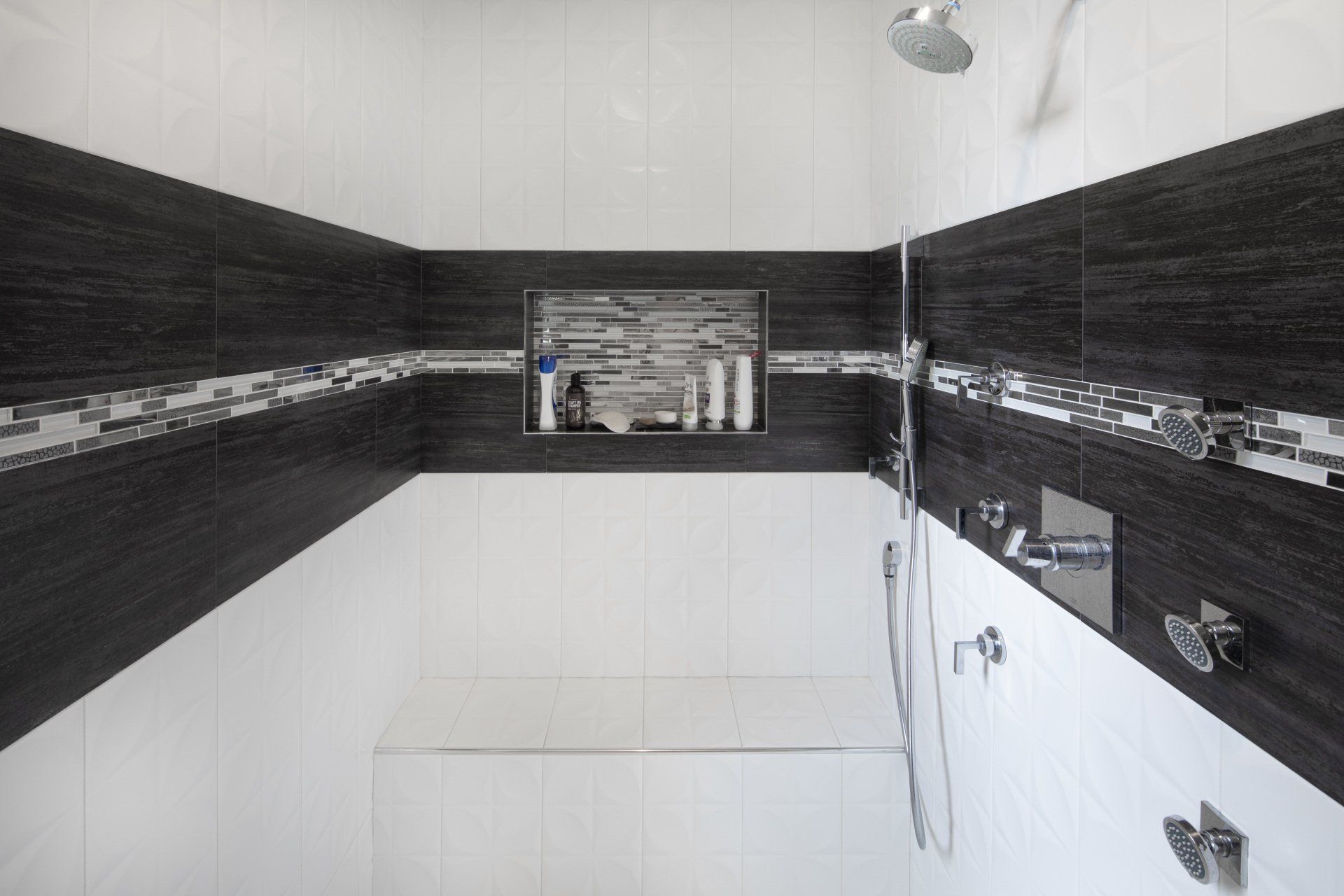 A bathroom with black and white tiles and a walk in shower.