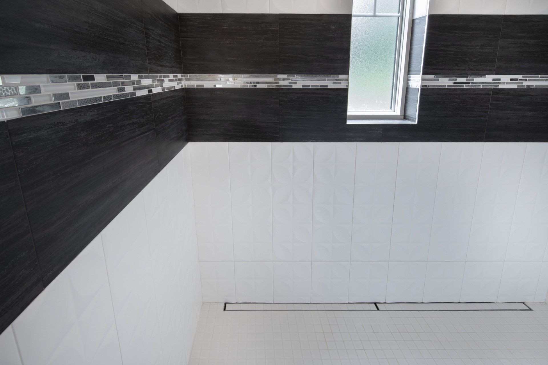 A bathroom with black and white tiles and a window.