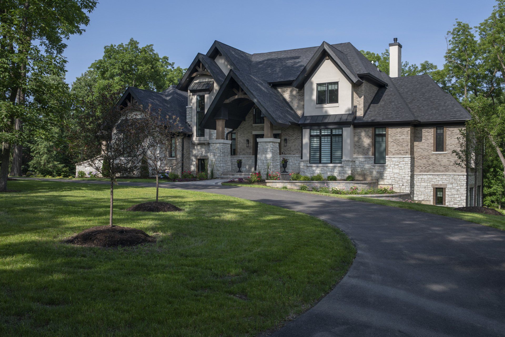 A large house with a driveway leading to it is surrounded by trees and grass.