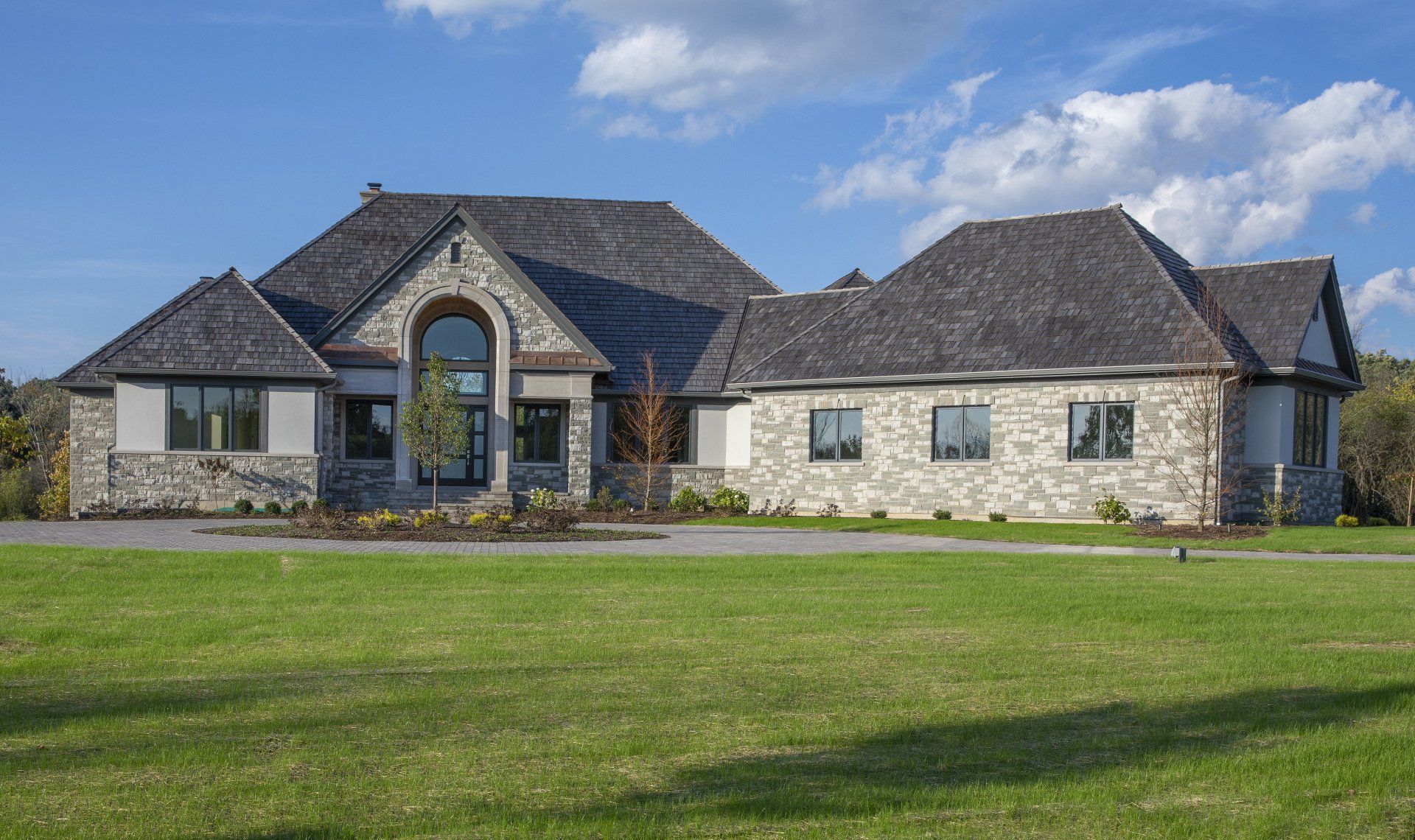 A large house is sitting on top of a lush green field.