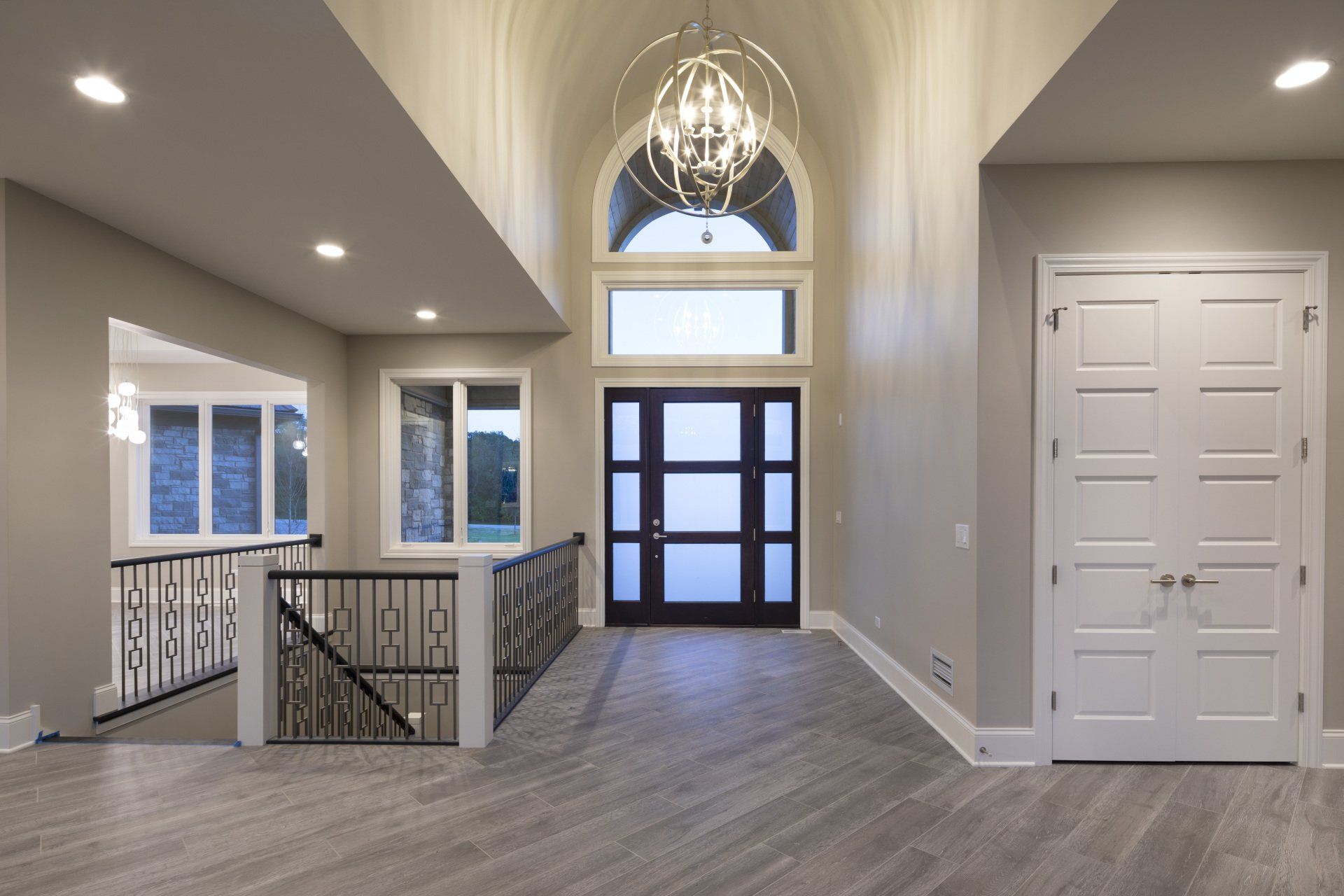 A large empty hallway with a staircase and a chandelier hanging from the ceiling.