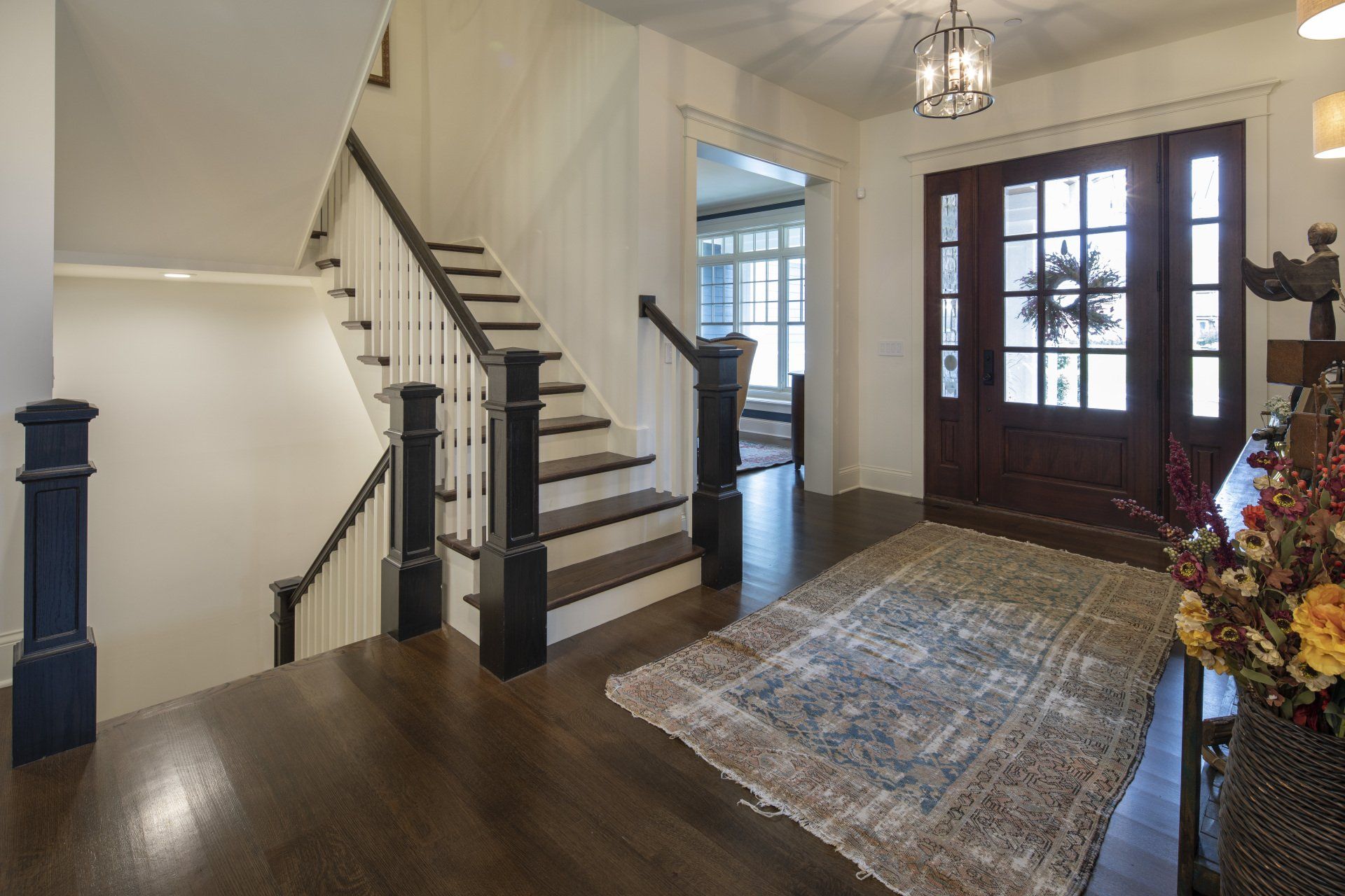 A hallway with stairs and a rug in a house.