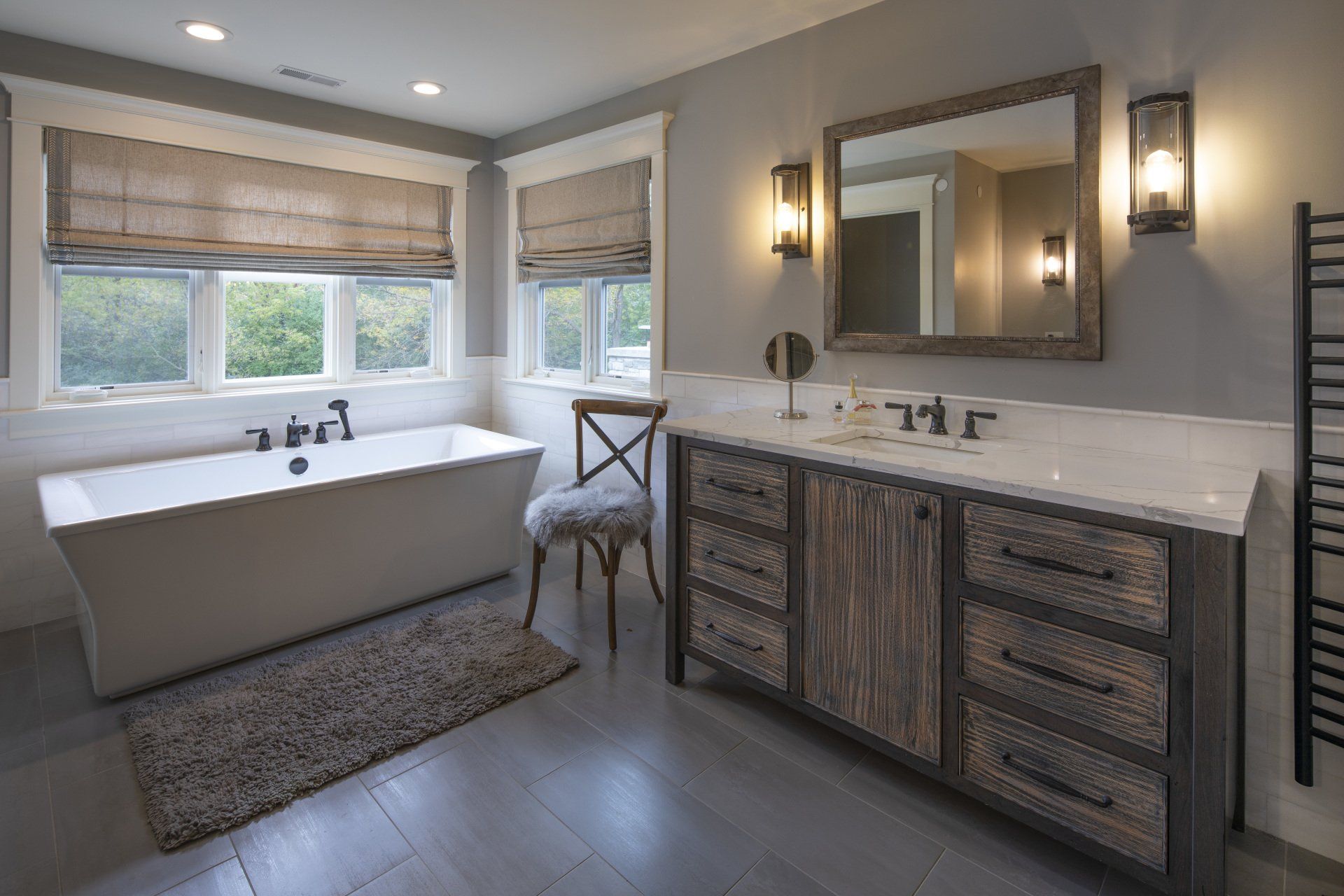 A bathroom with a tub , sink , mirror and chair.