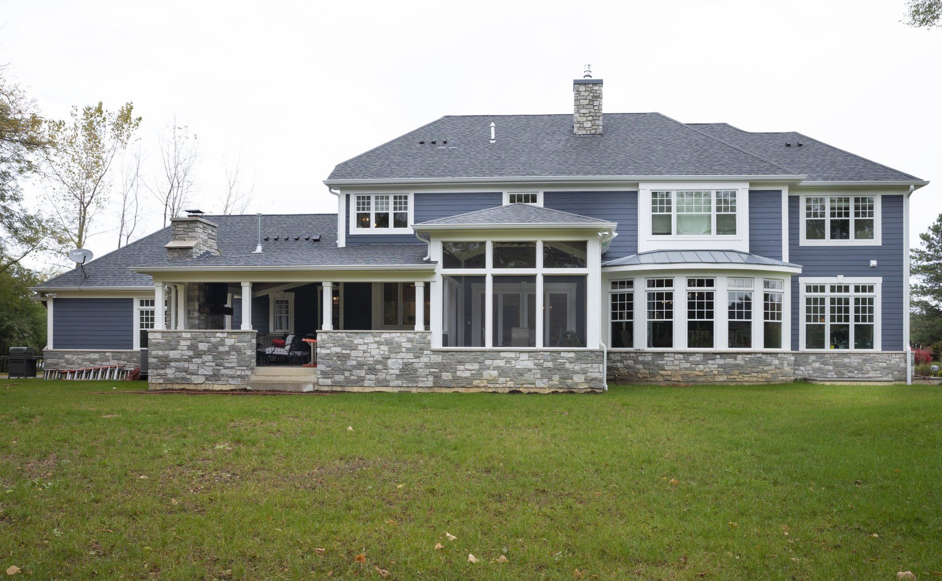 A large blue house with a screened in porch and lots of windows